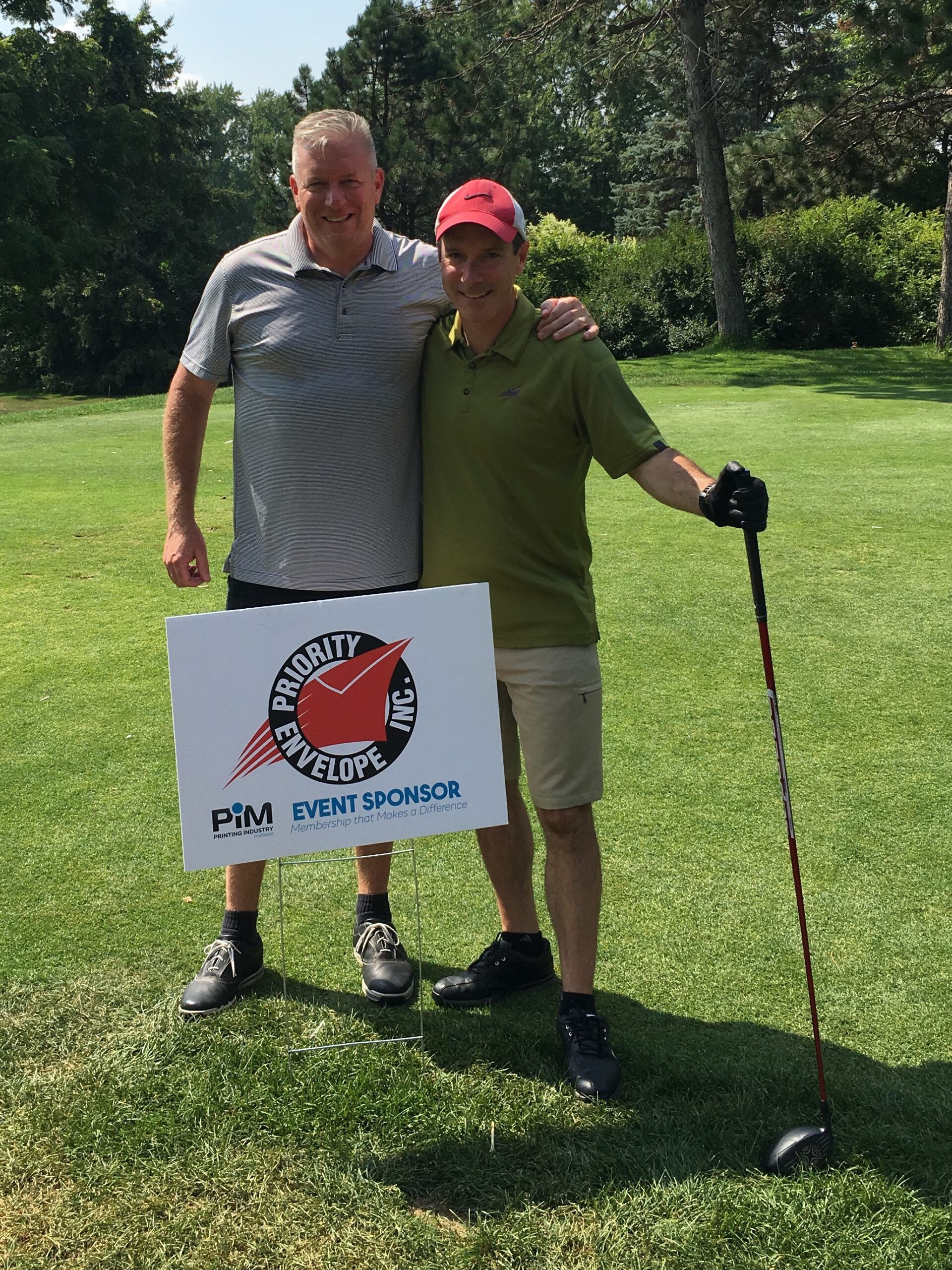 Two men smiling on a golf course next to priority envelop sign - mailing envelopes