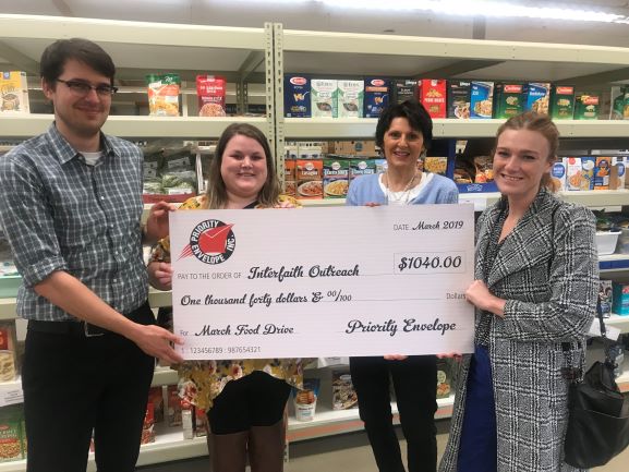 Interfaith Outreach Food Shelf team members accepting Priority Envelope's donations - pocket folders