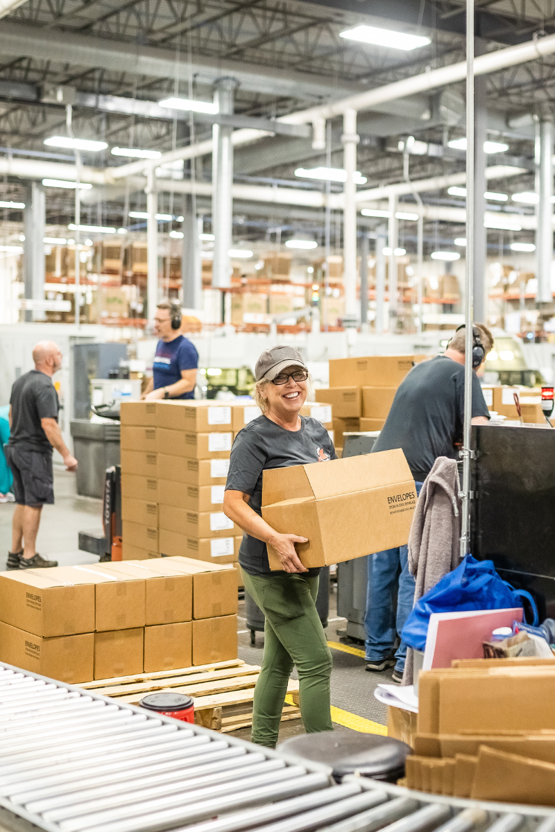 Woman carrying a box in a warehouse - custom printed boxes